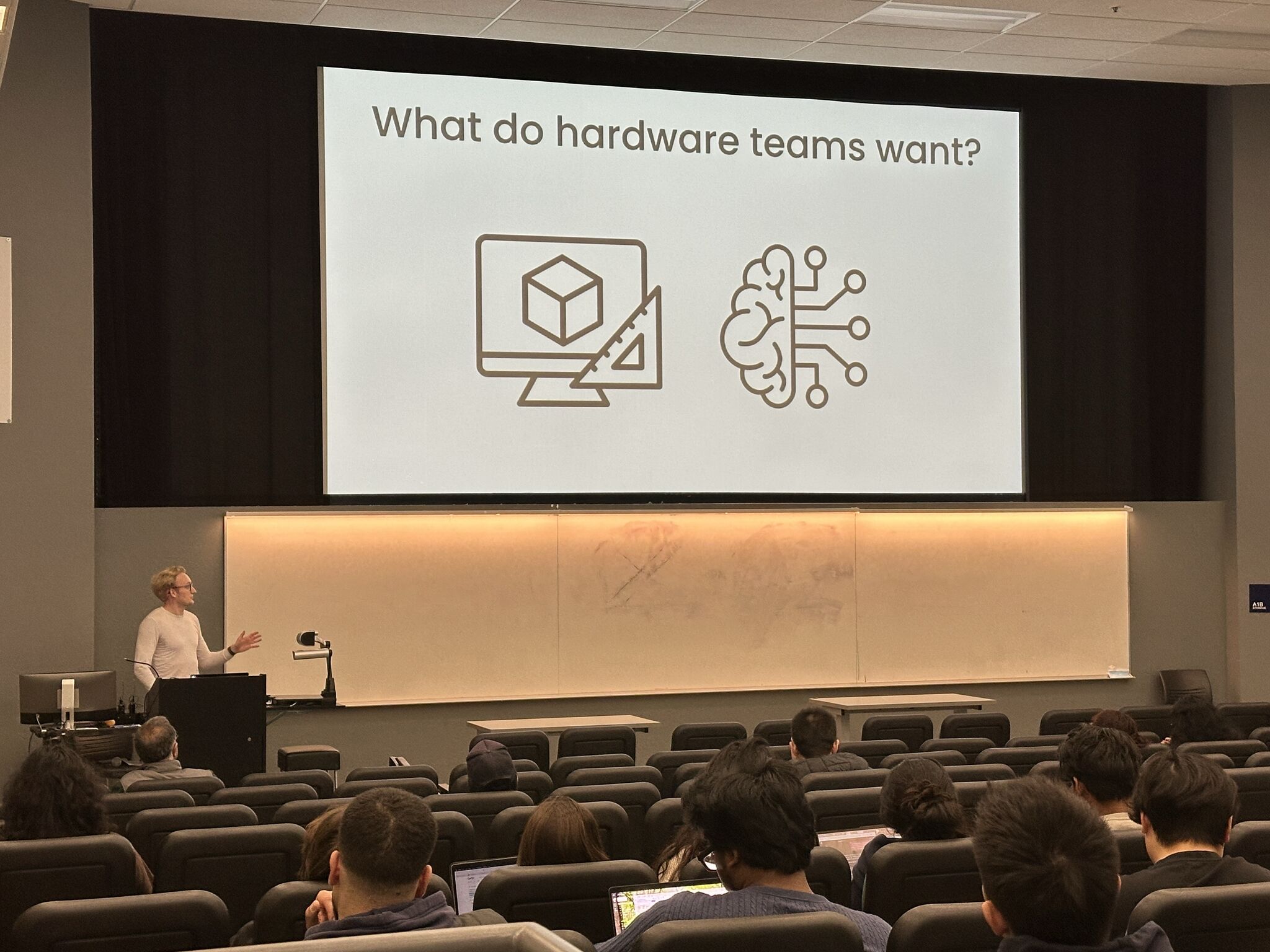 Eric Berndt lecturing at UC Berkeley, a slide asking "What do hardware teams want?" on the screen