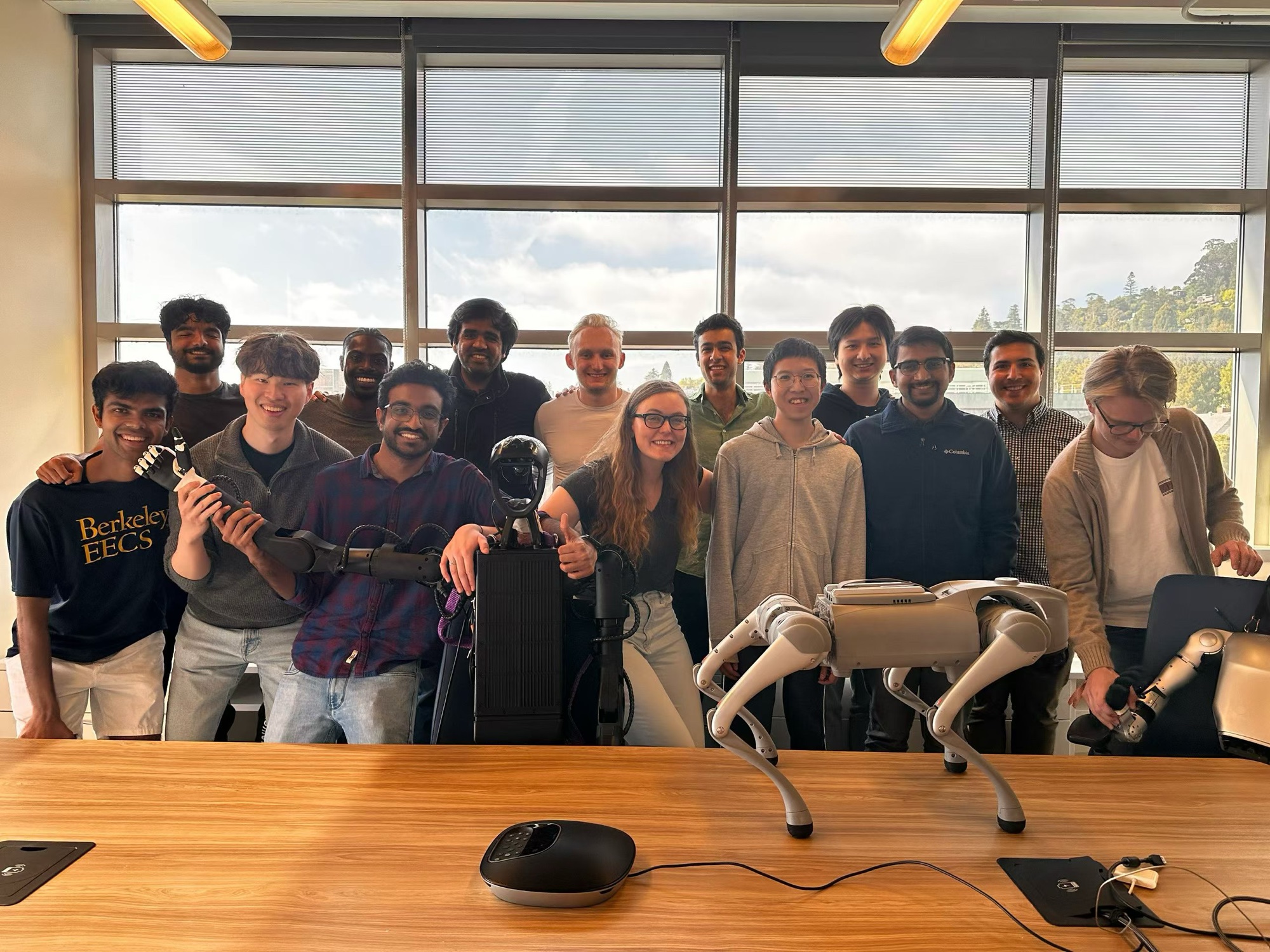 The Berkeley EECS lab group with a quadruped robot and a dexterous hand; founders Eric and C.K. among them, Adith just behind Kunal at the left