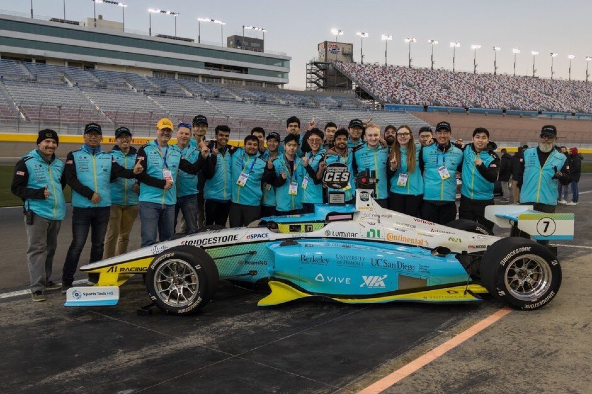 The AI Racing Tech team with their full-scale autonomous IndyCar at Las Vegas Motor Speedway; founders Adith, Eric, and C.K. among them